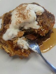 Toast with a double stack of gluten-free banana bread, dates, honey, bacon, flaked almonds, yoghurt and almond butter